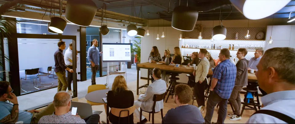 Teammeeting im offenen Büro der ORBIS SE mit Präsentation am Bildschirm, Szene aus dem Recruitingfilm