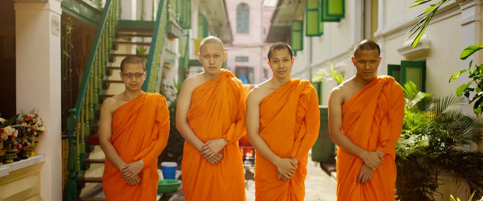 Vier Mönche in orangefarbenen Roben vor einem Innenhof in Thailand, Szene aus dem Wundrwatch Werbefilm