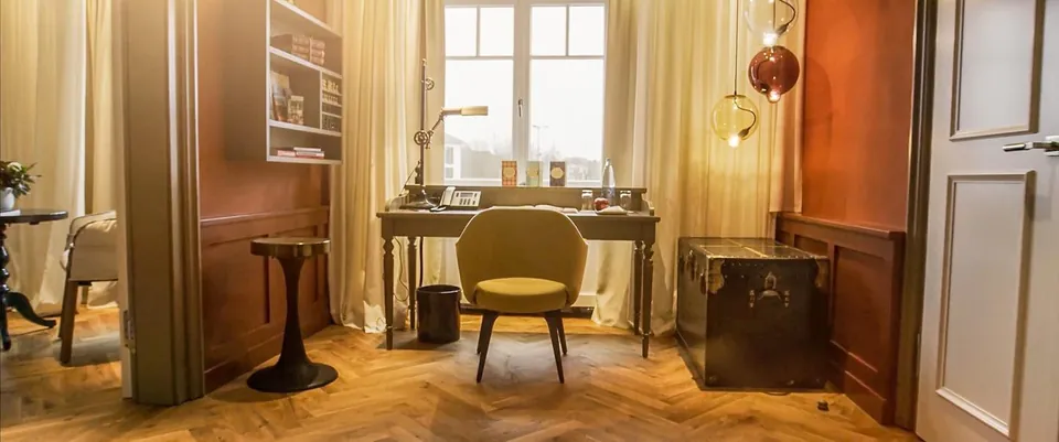 Stilvolles Hotelzimmer im La Maison Saarlouis mit Schreibtisch, Sessel und Fischgrätparkett